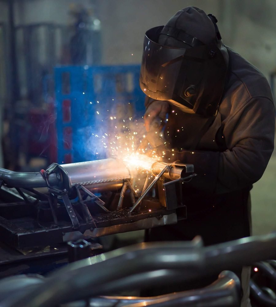 worker-welding-exhaust-pipes-pieces-together-1.jpg